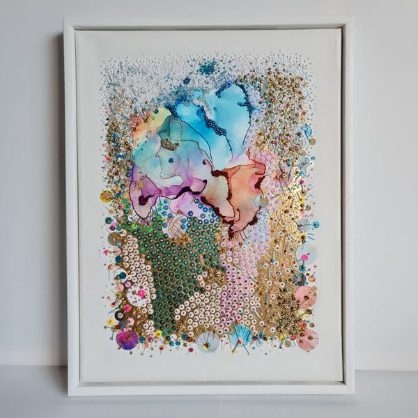 Abstract alcohol ink artwork with hand embroidery, beads, and gold threads on canvas in white frame.