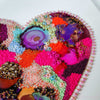 Close-up of embroidered and beaded colorful heart artwork with metallic thread and alcohol ink on canvas